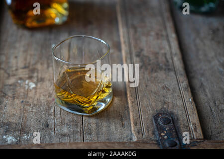Golden shimmering whisky in a glass on a shabby wooden old oak barrel Stock Photo