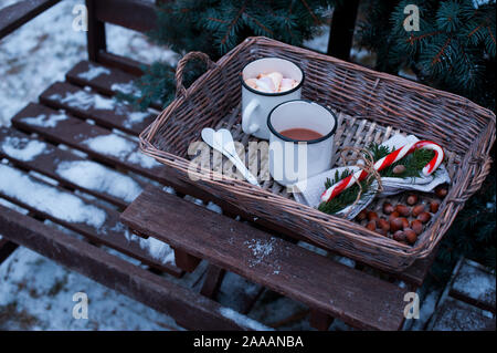 Two cups of hot cocoa in a wicker basket on a wooden table. Stock Photo