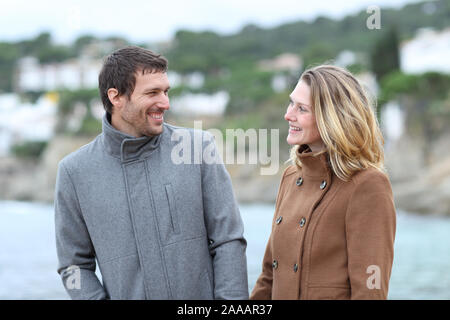 Happy man and woman talking and walking on the beach in winter Stock Photo