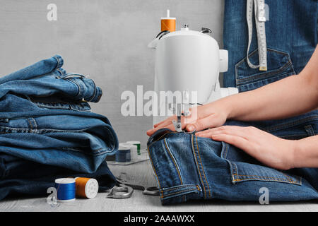 Sewing denim jeans on sewing machine in tailor workshop. Jeans repair. Stock Photo