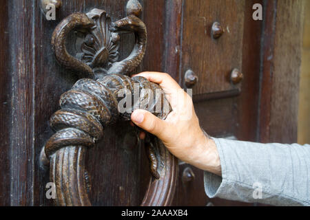 Close-up male hand on a huge antique doorknob ring, selective focus Stock Photo
