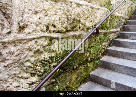 Close-up of a metal railing at a medieval stone staircase covered with green moss, selective focus Stock Photo