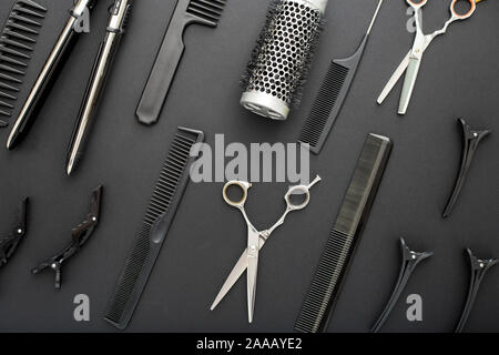 Flat lay composition with Hairdresser tools: scissors, combs, hair iron on black background. Frame. Hairdresser service. Beauty salon service Stock Photo