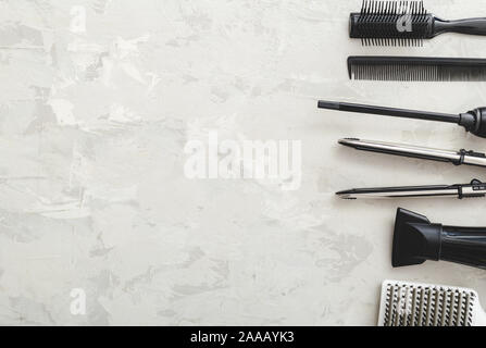 Flat lay composition with Hairdresser tools: scissors, combs, hair iron, hair dryer on gray background with copy space for text. Frame. Hairdresser Stock Photo