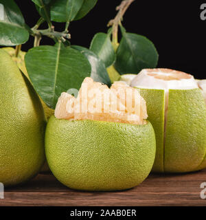 Fresh peeled pomelo, grapefruit, shaddock with green leaves on dark wooden plank table. Seasonal fruit near mid-autumn festival, close up, copy space Stock Photo