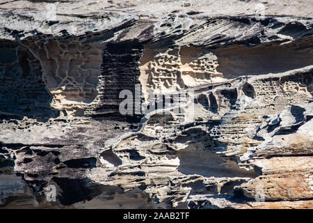 Sandstone cliff rock face layers weathered by seaside, ideal as natural geologic background Stock Photo