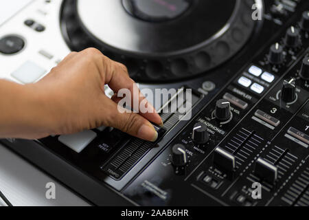 Hands of DJ mixing tracks on professional sound mixer.Fashionable rings on fingers of girl disc jockey playing music.Closeup,knobs and regulators in Stock Photo