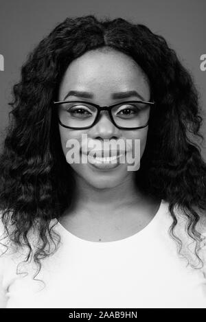 Young beautiful African woman wearing eyeglasses against gray background Stock Photo