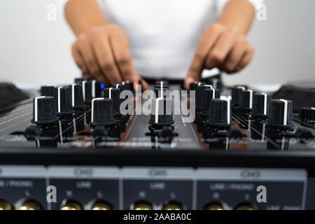 Hands of DJ mixing tracks on professional sound mixer.Fashionable rings on fingers of girl disc jockey playing music.Closeup,knobs and regulators in Stock Photo