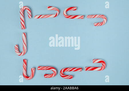 Candy canes arranged in a frame on blue background - top view with copy space Stock Photo