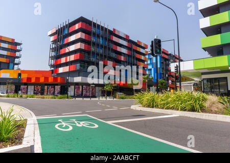 Gold Coast Australia - November 19 2019; Modern trendy bright colors apartment blocks from street with green cycle land and cycle graphic. Stock Photo