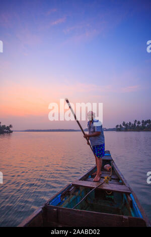 A fisherman on his wooden boat in Suvarna river near Udupi (Karnataka, India). This is a sunrise scene. Stock Photo