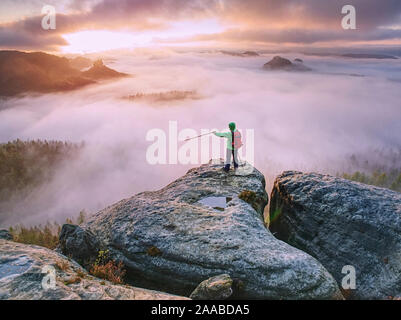 Hiker found attractive place on trail in sandstone rocky towers. Autumn misty morning in pure nature. Tourist use outdoor equipment Stock Photo