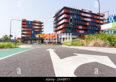 Gold Coast Australia - November 19 2019; Modern trendy bright colors apartment blocks from street with large white direction arrows on street. Stock Photo