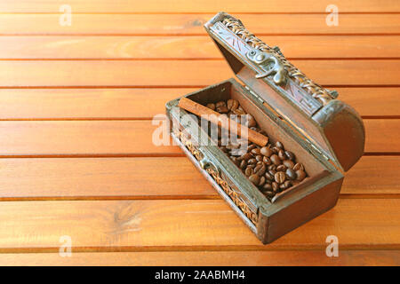 Vintage wooden case of roasted coffee beans with cinnamon stick isolated on wooden table Stock Photo