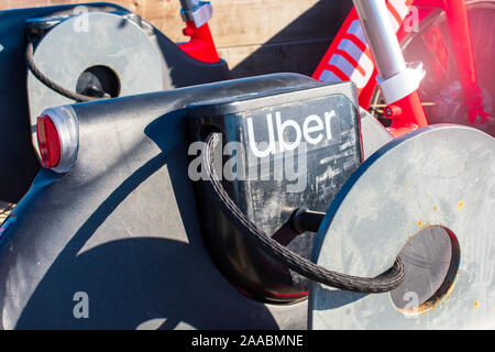 Close up. Uber logo on JUMP pedal-assist electric bike locked with cable lock to public bike rack - Santa Cruz, California, USA - 2019 Stock Photo