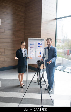 Couple of successful entrepreneurs filming online tutorial for young businessmen Stock Photo