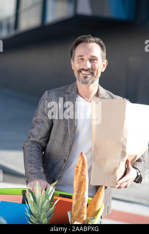 Bearded businessman holding bag with foods after groceries shopping Stock Photo