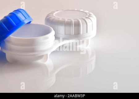 Contact lens case open reflected on white glass table. Horizontal composition. Elevated view. Stock Photo