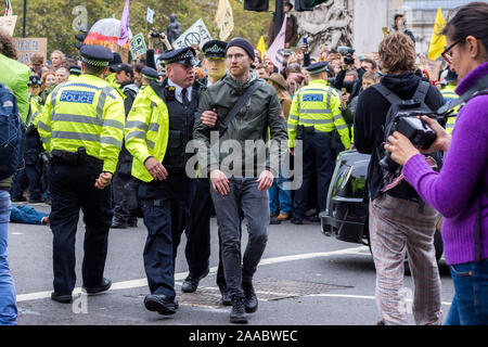 London, England –October 11, 2019: Extinction Rebellion protester arrested by police forces in Trafalgar Square London Stock Photo