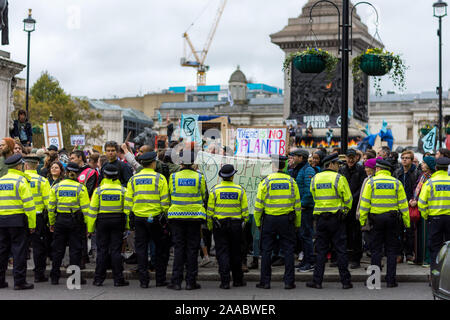 London, England –October 11, 2019:  Police forces overlooking Extinction Rebellion protesters in Trafalgar Square London Stock Photo