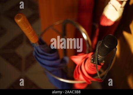 Set of three closed umbrellas in a metal stand Stock Photo