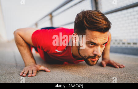 Beautiful male runner stretching before workout, fit man doing exercises outdoors