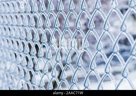 Ice on a fence made of metal mesh. Icy rain in the winter. Atmospheric phenomena of nature. Selective focus, close up. Stock Photo