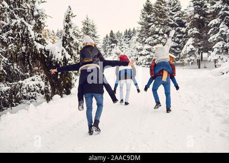 Playful men and women having fun in winter woods Stock Photo