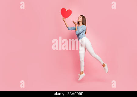 Full length body size side brown haired profile photo of cheerful positive cute pretty nice tender girl sending air kiss to heart held isolated pastel Stock Photo