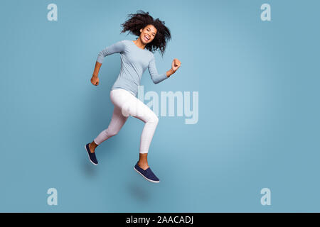 Full length body size turned photo of cheerful positive cute nice girlfriend wearing white pants running jumping footwear isolated pastel color Stock Photo