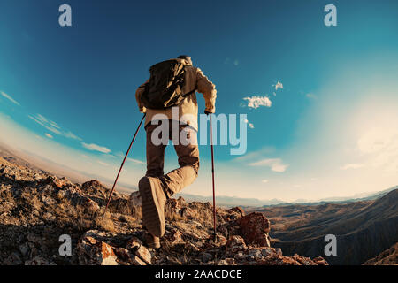 Hiker man goes in mountains area at sunset time Stock Photo