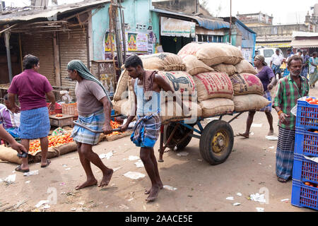 Day labourers pulling cart with goods at the outdoor market  in Tiruchirappalli, Tamil Nadu, India Stock Photo