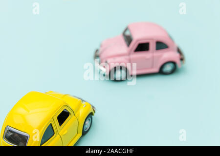 Simply design with two yellow pink vintage retro toy car isolated on blue pastel colorful background. Automobile and transportation symbol. City traffic delivery concept. Copy space for text Stock Photo