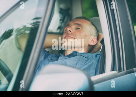 Man sleeping in the car before next part of the journey Stock Photo