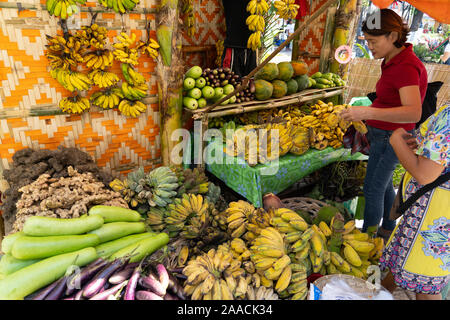 A woman choosing fruit from a fruit & vegetable stall within a farmers market,Cebu City,Philippines Stock Photo