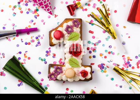 Number one cake decorated with flowers, macarons and confetti isolated on white background Stock Photo