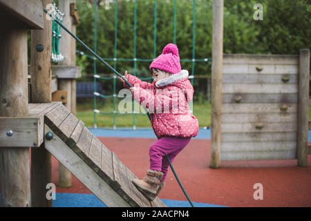 toddler girl climbing at winter playground,Northern Ireland Stock Photo