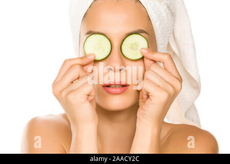 Young woman posing with slices of cucumbers on her eyes on white background Stock Photo