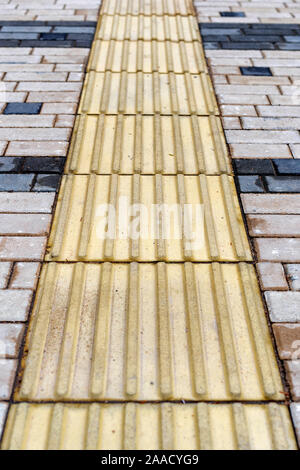 An adapted environment for visually impaired people in a modern city. A special pavement coating is tactile tiles for the disabled. Stock Photo