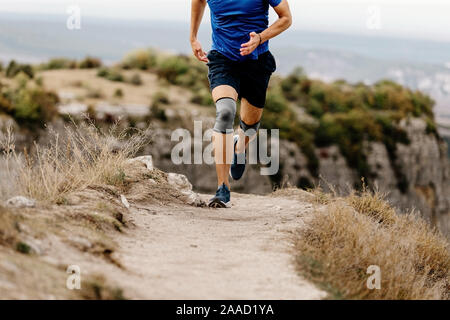 athlete runner knee injury run in knee pads on mountain trail Stock Photo