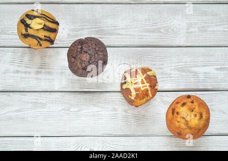 Sweet and tasty snack. Three different colorful cupcakes on a wooden background. Stock Photo