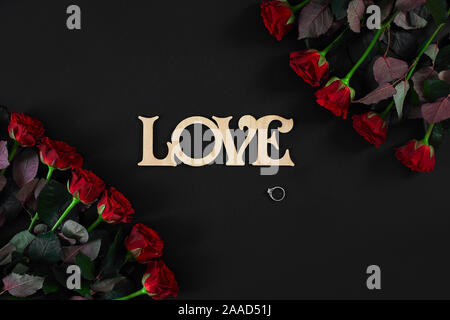 Red roses flowers with wooden word LOVE on black background with Stock Photo