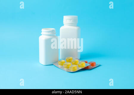 White medical bottles and different pills in blister packs on blue background, space for text Stock Photo