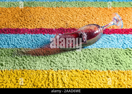 Glass of red wine falling over the carpet Stock Photo