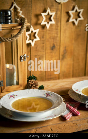 Christmas plate of delicious home made broth on wooden table Stock Photo
