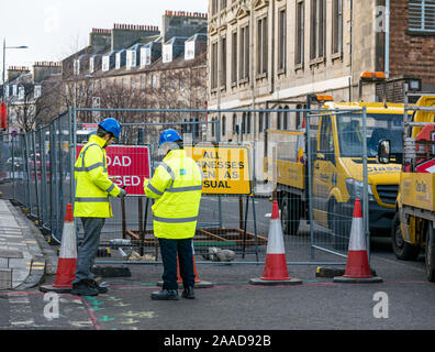 Leith, Edinburgh, Scotland, United Kingdom. 21st Nov, 2019. Trams to Newhaven work starts: Constitution Street is closed to traffic for the next 2-3 years to build the extension for Edinburgh's tram line from to Newhaven, with 8 more stops over 2.91 miles. Barriers are put up along the road. The work is being undertaken by SFN (Sacyr Farrans Neopul) and MUS (Morrison Utility Services). Men with Trams to Newhaven yellow jackets wearing hard hats next to a road closed sign Stock Photo