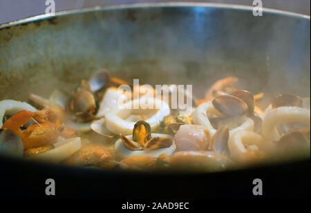 Cooking mussels, prawns and crabs on a pan. Close-up view of sea food in a frying pan. Tranditional cooking Stock Photo