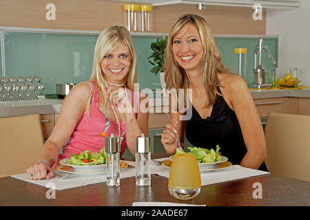 Zwei Frauen sitzen in der Kueche und essen Salat Stock Photo