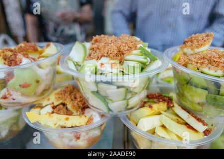 Fresh peeled sliced sour crispy mangoes with spicy salt dips on top, Thai snack fruit for sale in a local street food market in Bangkok, Thailand. Stock Photo